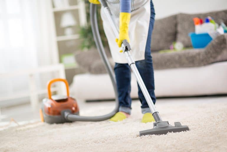 Man cleaning carpet with Vacuum Cleaner